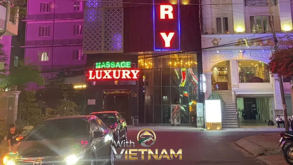 밤거리의 마사지 샵 유리 입구와 주차된 차량들