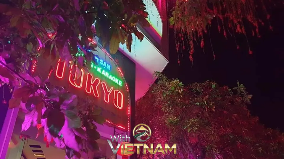 나뭇잎 사이로 보이는 붉은색 도쿄 호텔 가라오케 네온 간판