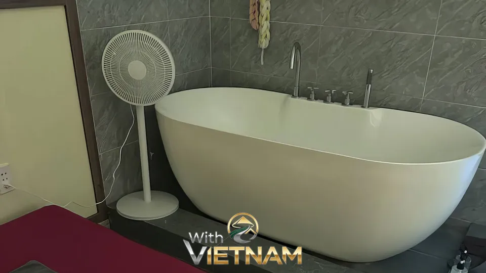 회색 타일 욕실에 놓인 흰색 욕조와 선풍기